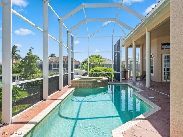 view of swimming pool featuring glass enclosure, an in ground hot tub, and a patio area