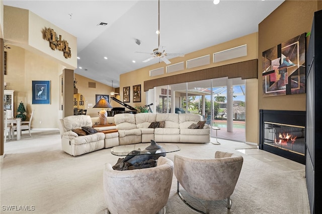 carpeted living room with ceiling fan and high vaulted ceiling