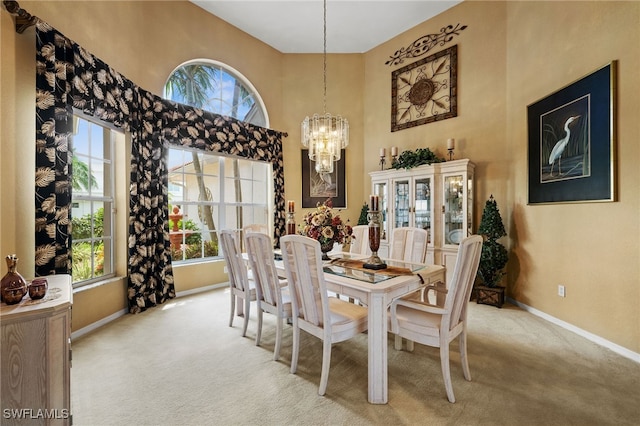 carpeted dining space featuring a chandelier and a high ceiling