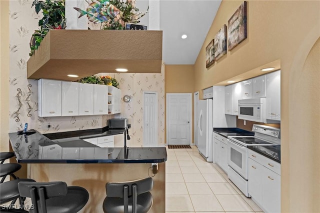 2512 SW 28th Pl, Cape Coral, FL 33914 - kitchen with white appliances, dark countertops, a peninsula, light tile patterned floors, and high vaulted ceiling