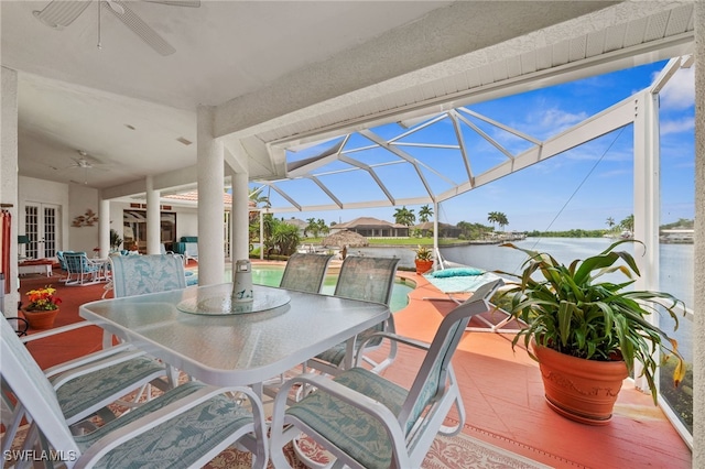 view of patio / terrace with ceiling fan, a water view, glass enclosure, and a swimming pool