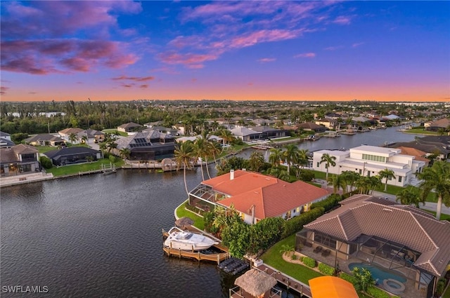 aerial view at dusk featuring a residential view and a water view