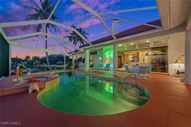 outdoor pool featuring a patio area, glass enclosure, and an in ground hot tub