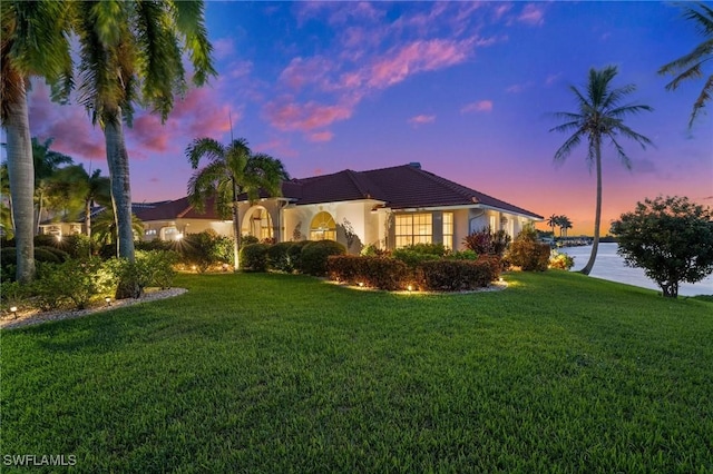 mediterranean / spanish-style house featuring a lawn and stucco siding