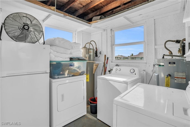 laundry area with a healthy amount of sunlight, washing machine and dryer, and water heater