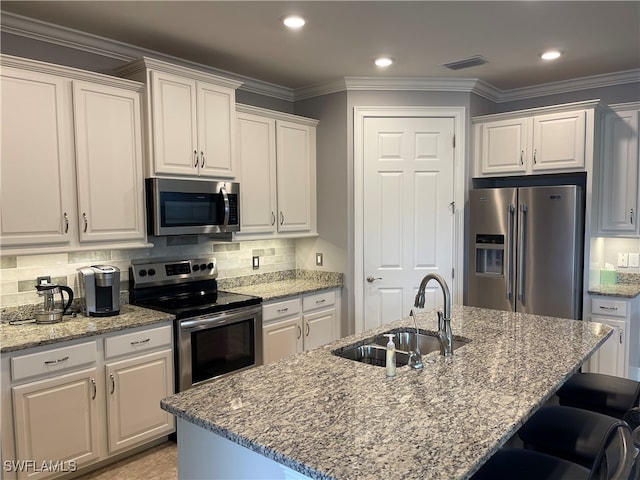 kitchen featuring sink, tasteful backsplash, a center island with sink, white cabinetry, and appliances with stainless steel finishes