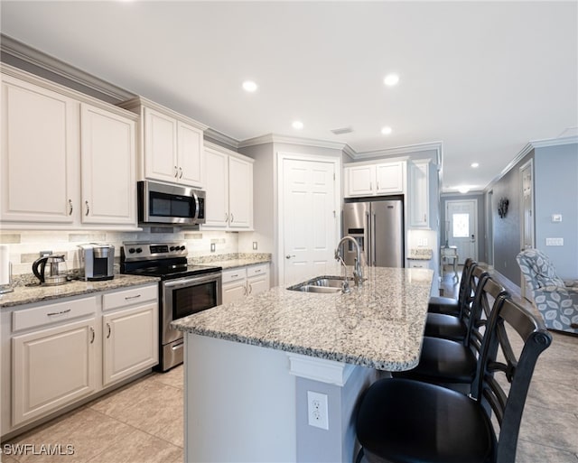 kitchen with appliances with stainless steel finishes, white cabinetry, sink, and an island with sink