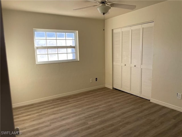 unfurnished bedroom with ceiling fan, a closet, baseboards, and dark wood-style flooring