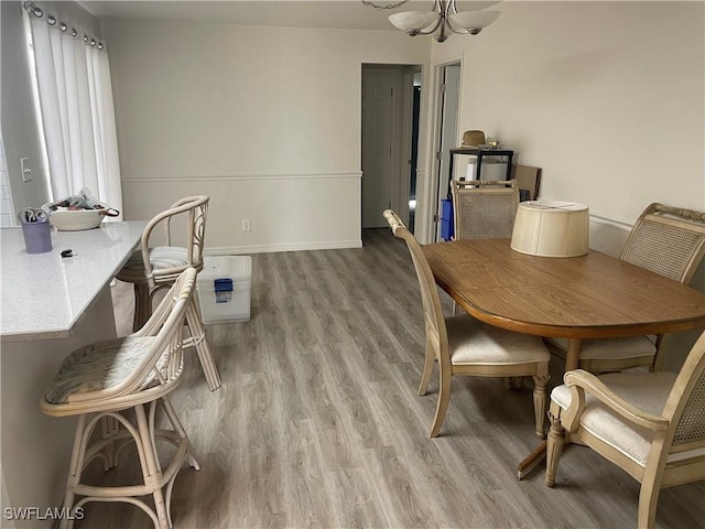 dining area with an inviting chandelier, light wood-style flooring, and baseboards