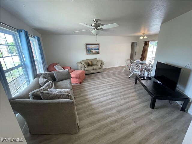 living area with a ceiling fan, baseboards, and wood finished floors