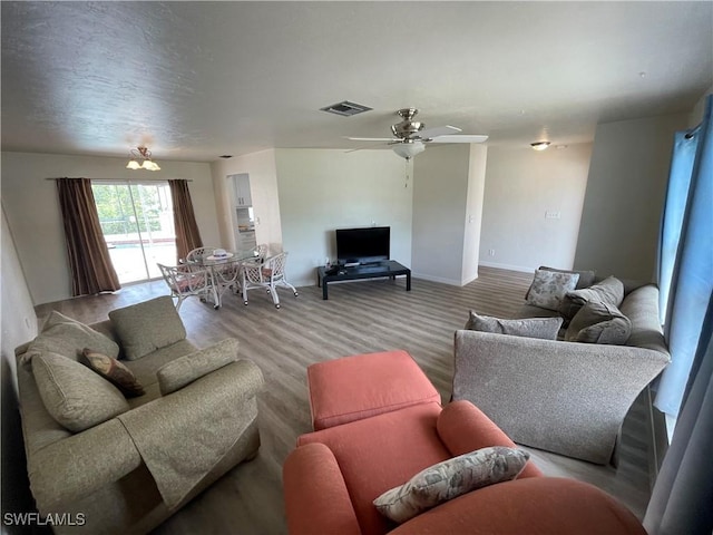 living area with a ceiling fan, visible vents, and baseboards