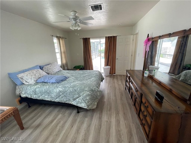 bedroom with visible vents, light wood-style flooring, a ceiling fan, a textured ceiling, and access to outside