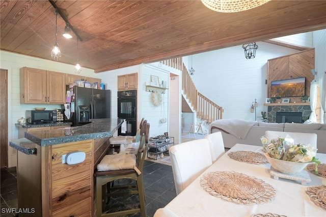 kitchen featuring wood ceiling, dark tile patterned floors, black appliances, rail lighting, and a fireplace