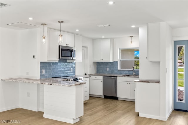 kitchen featuring hanging light fixtures, appliances with stainless steel finishes, white cabinetry, light hardwood / wood-style flooring, and kitchen peninsula