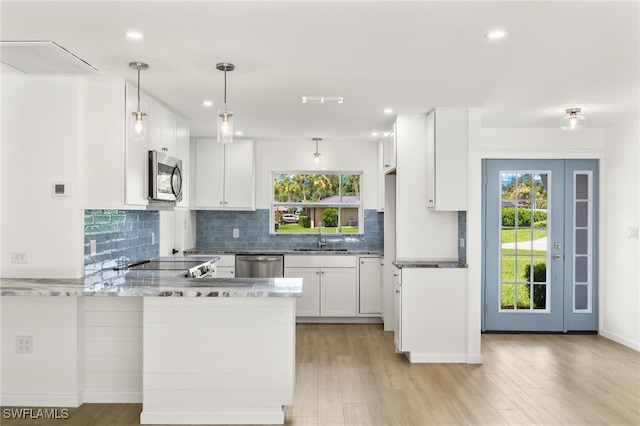 kitchen featuring kitchen peninsula, white cabinetry, stainless steel appliances, and light hardwood / wood-style floors