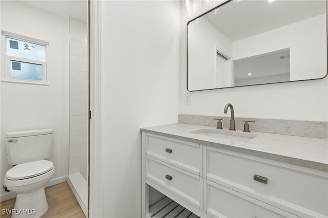 bathroom featuring walk in shower, wood-type flooring, vanity, and toilet