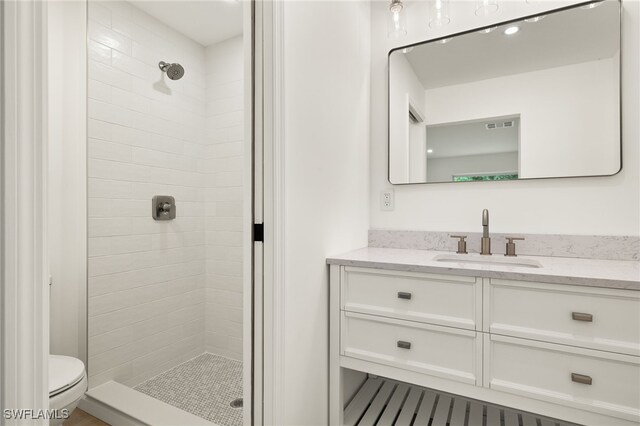 bathroom with tiled shower, toilet, and vanity