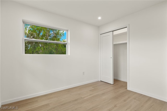 unfurnished bedroom with light hardwood / wood-style flooring and a closet