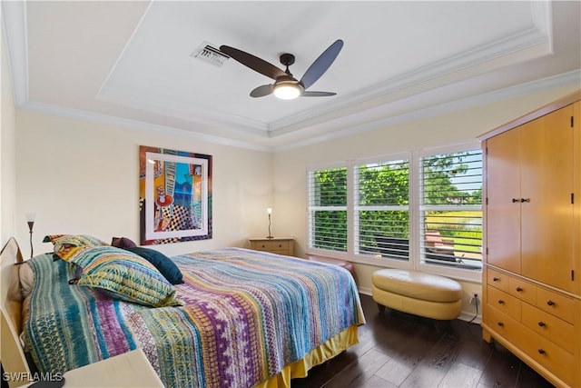 bedroom with dark wood finished floors, a tray ceiling, and visible vents