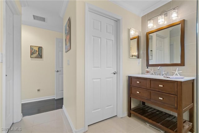 bathroom featuring tile patterned flooring, visible vents, baseboards, ornamental molding, and vanity