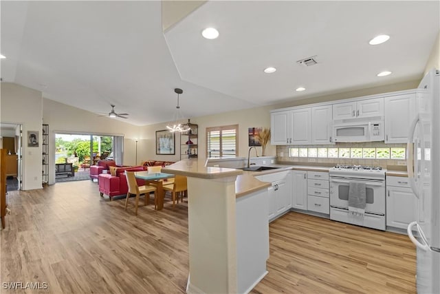 kitchen featuring a sink, open floor plan, white appliances, a peninsula, and light wood finished floors