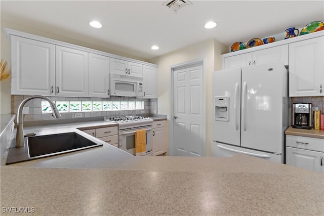 kitchen featuring sink, white appliances, white cabinets, and backsplash