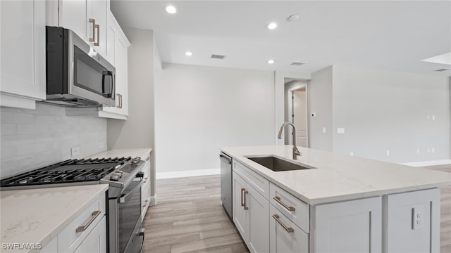 kitchen with light hardwood / wood-style flooring, backsplash, an island with sink, appliances with stainless steel finishes, and sink