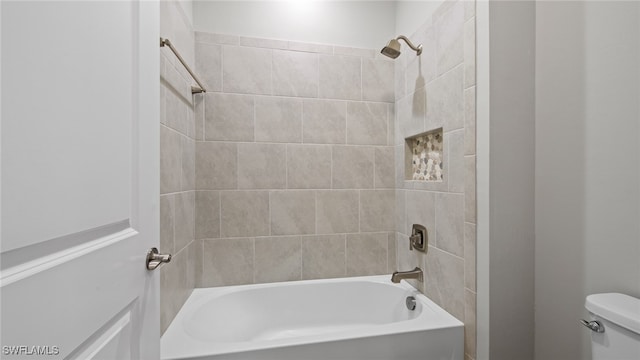 bathroom with tiled shower / bath combo and toilet