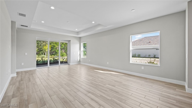 unfurnished room featuring light hardwood / wood-style floors and a raised ceiling