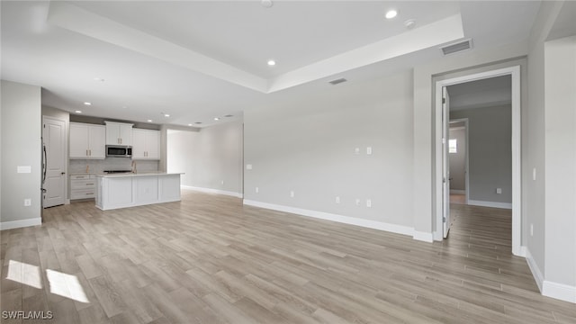 unfurnished living room featuring light hardwood / wood-style flooring and a tray ceiling