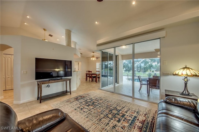 living room featuring arched walkways, lofted ceiling, visible vents, a ceiling fan, and light tile patterned flooring