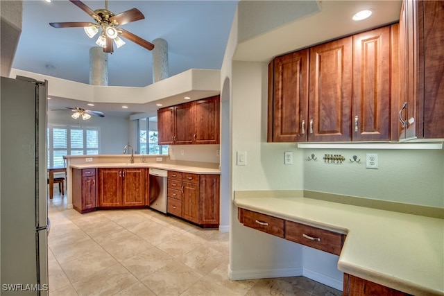 kitchen featuring stainless steel appliances, a peninsula, a ceiling fan, light countertops, and brown cabinetry