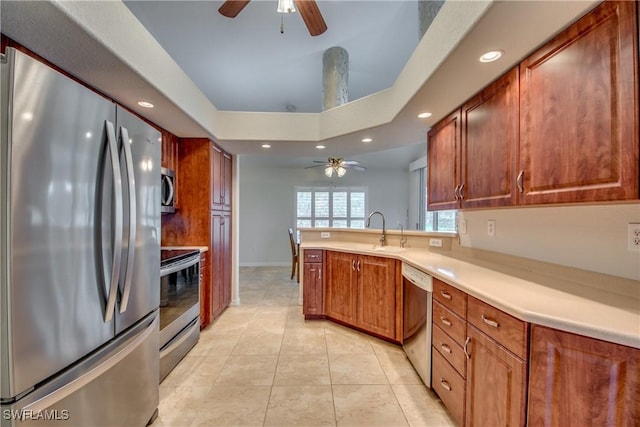 kitchen with a raised ceiling, light countertops, appliances with stainless steel finishes, a sink, and a peninsula