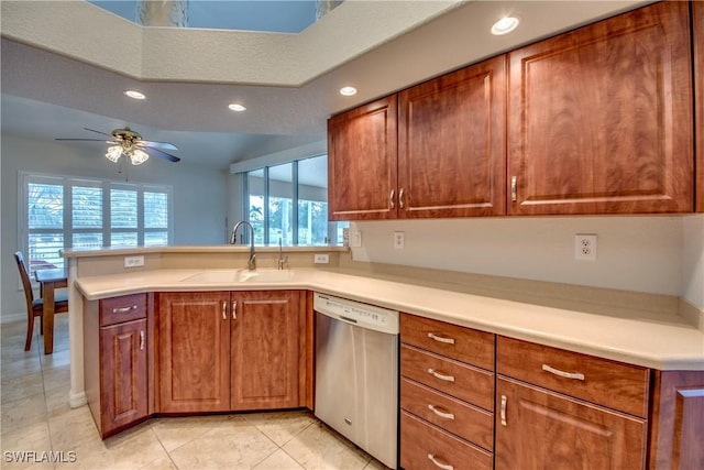 kitchen with brown cabinetry, dishwasher, a peninsula, light countertops, and a sink