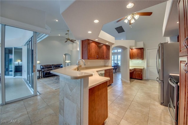 kitchen with light countertops, open floor plan, light tile patterned flooring, a sink, and a peninsula