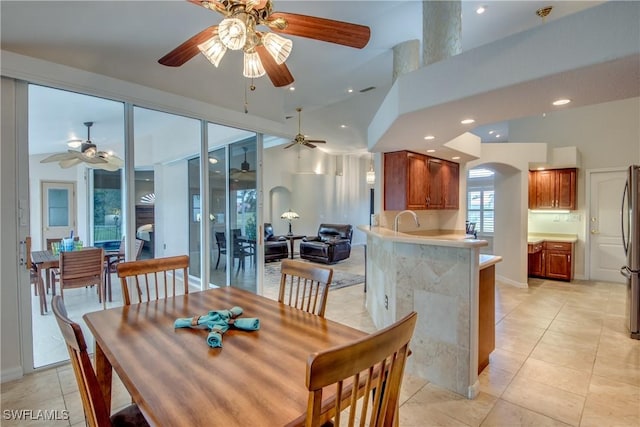 dining area with arched walkways, ceiling fan, light tile patterned flooring, recessed lighting, and a high ceiling