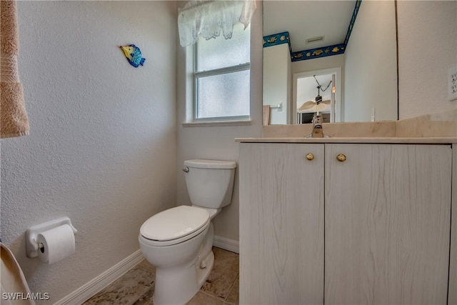 bathroom with a textured wall, toilet, vanity, tile patterned flooring, and baseboards