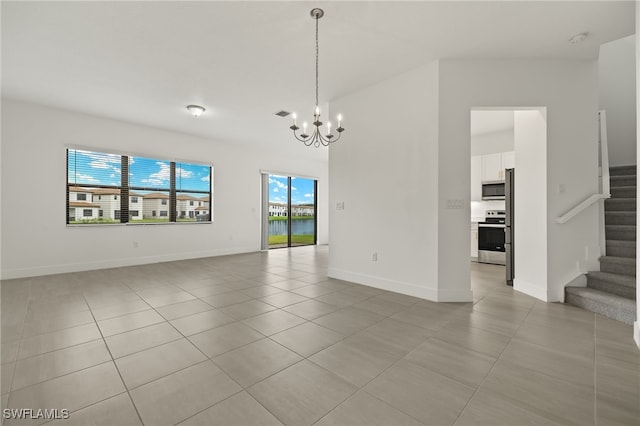 empty room with a notable chandelier and light tile patterned flooring