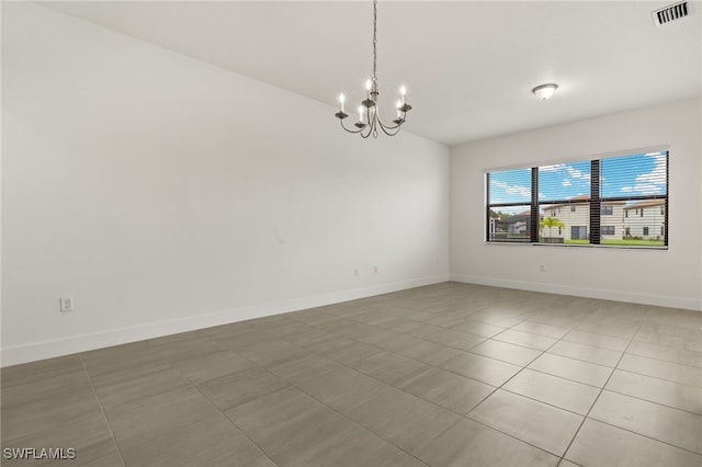 tiled empty room featuring a chandelier