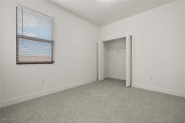 unfurnished bedroom featuring light colored carpet and a closet