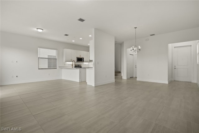 unfurnished living room featuring sink, light tile patterned floors, and a notable chandelier