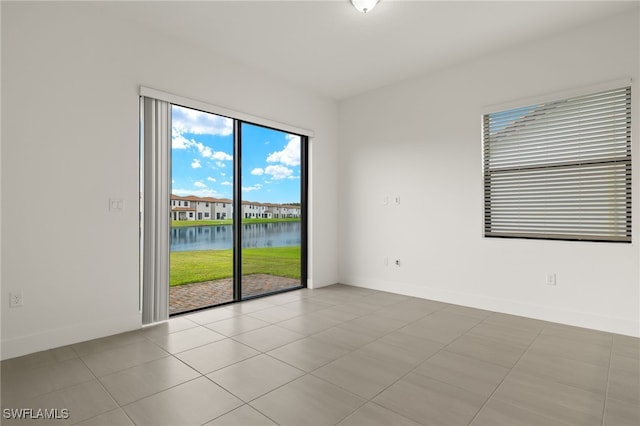 empty room featuring light tile patterned floors and a water view