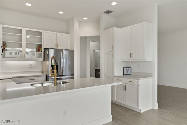 kitchen featuring white cabinets, light tile patterned floors, and stainless steel refrigerator