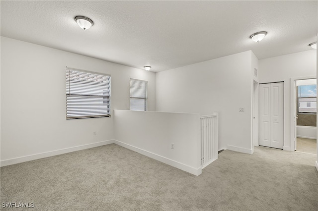 carpeted empty room with a textured ceiling