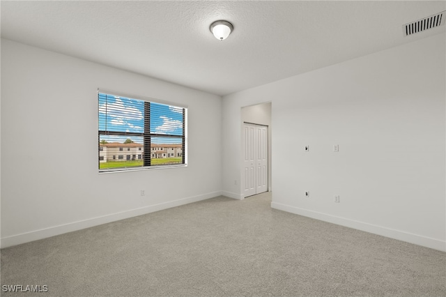 empty room featuring a textured ceiling and light colored carpet