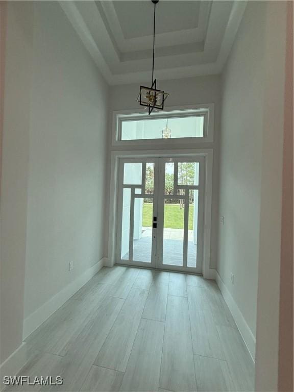 788 9th St SW, Naples, FL 34117 - entryway featuring a tray ceiling, a chandelier, french doors, light wood-type flooring, and a high ceiling
