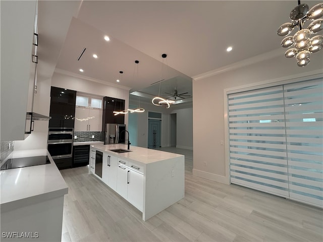 kitchen featuring a kitchen island with sink, sink, decorative backsplash, decorative light fixtures, and stainless steel appliances