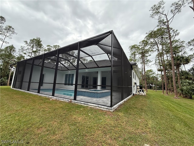 back of property with a swimming pool with hot tub, a lanai, and a yard