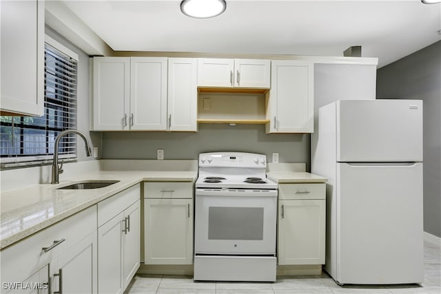 kitchen featuring white appliances, light tile patterned floors, white cabinets, light stone counters, and sink