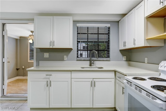 kitchen with electric range, white cabinetry, light tile patterned floors, ceiling fan, and sink